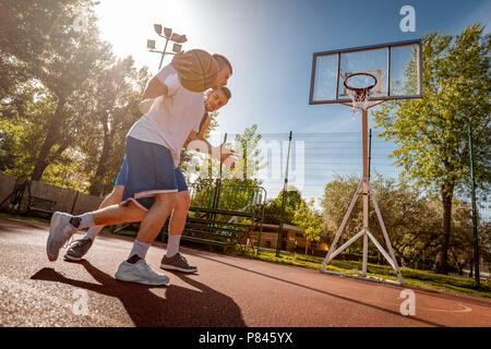 Due street i giocatori di basket a giocare uno contro uno. Essi stanno compiendo una buona azione e custodire la sfera. Foto Stock