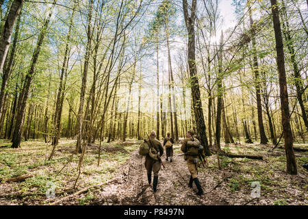 Gruppo di re-enactors vestito come Soviet russo Rosso esercito di soldati di fanteria della II Guerra Mondiale in marcia lungo la strada forestale a stagione primaverile. Foto Stock