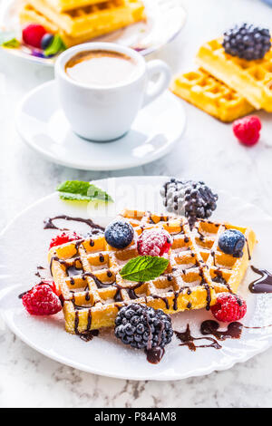 Cialde fresche con lo sciroppo al cioccolato bacche polvere di zucchero e le foglie di menta. Foto Stock