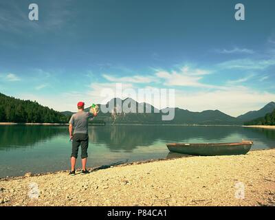 Photo Traveler sta prendendo foto di memoria del paesaggio lacustre. Lago Blu tra alte montagne, picchi toccare nel cielo blu. Viaggio il concetto di stile di vita Foto Stock