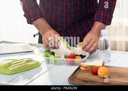 Uomo che fa scuola pranzo sano nella mattinata con la cucina domestica Foto Stock