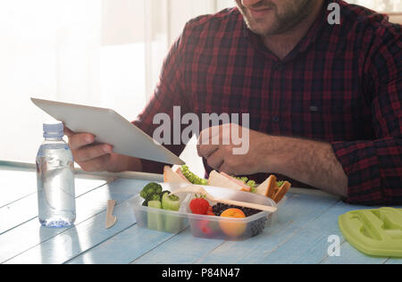 L'uomo ha una sana prima colazione nel suo ufficio di casa. Concetto di mangiare sano Foto Stock