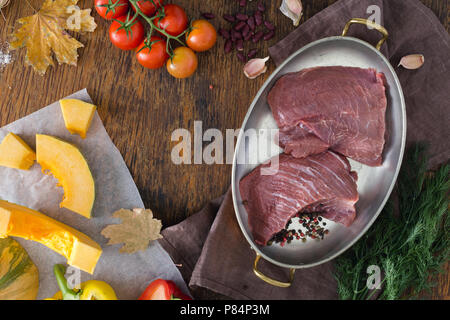 In autunno l'umore. Pezzi di carne di manzo crudo con verdure (zucca, aneto, pepe, pomodori aglio), fagioli e foglie di autunno sul tavolo di legno con copia spazio. In Foto Stock