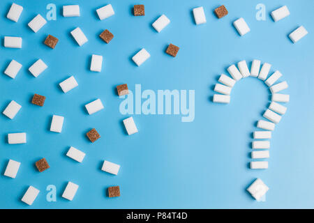 Zollette di zucchero a forma di punto interrogativo segno su sfondo blu. Foto Stock