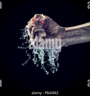 Le mani umane tentare di serrare acqua su sfondo nero Foto Stock