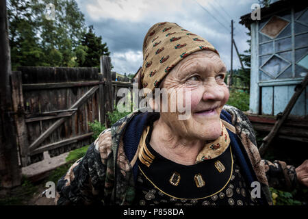 Una vecchia donna sorridente, in Kazakistan, davanti a casa sua. Foto Stock