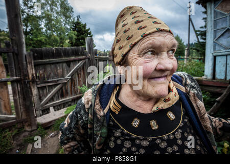 Una vecchia donna sorridente, in Kazakistan, davanti a casa sua. Foto Stock