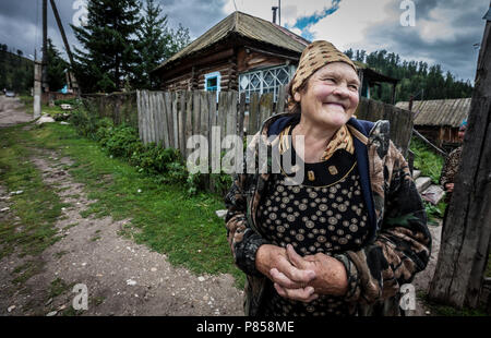 Una vecchia donna sorridente, in Kazakistan, davanti a casa sua. Foto Stock