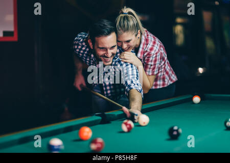 Coppia giovane giocare biliardo insieme in bar Foto Stock