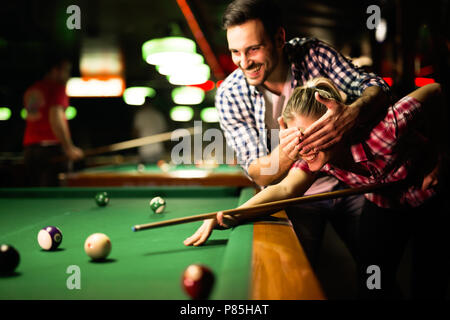 Coppia giovane giocare biliardo insieme in bar Foto Stock