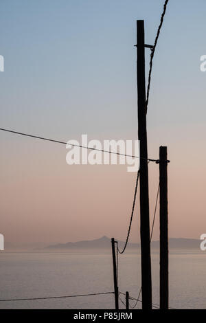 Linee elettriche collegate a pali di legno con le isole Saroniche e il golfo sullo sfondo, Saronida, Attica orientale, Grecia Foto Stock