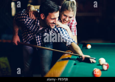 Coppia giovane giocare biliardo insieme in bar Foto Stock