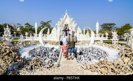 Visitatori guardando l'attenzione progettuale mani sculture prima la "Porta del Cielo" in Wat Rong Khun, bianco tempio, Chiang Rai, Thailandia del Nord Foto Stock