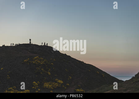 I turisti presso la Arthur's sedile rispettando il mare di nebbia (haar) travolgendo Edimburgo, capitale della Scozia, poco prima del tramonto. Foto Stock