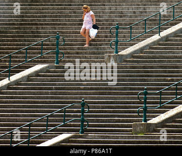 Ragazza in abiti rosa cammina verso il basso di una vecchia scala, al boulevard di Vlissingen Foto Stock