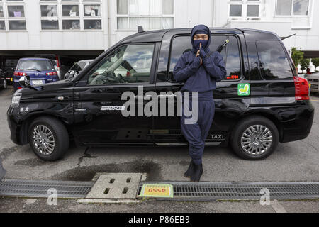 9 luglio 2018 - Yokohama, Giappone - un tassista vestito in costume Ninja in posa per una fotografia accanto al suo esterno cabina Sanwa Koutsu gruppo compagnia di taxi a Yokohama. Yokohama basata su provider taxi Sanwa Koutsu Group ha lanciato un nuovo servizio chiamato ''Ninja de Taxi'' per attirare gli enti locali e i clienti esteri. Il ninja costume cab driver forniscono un esperienza unica per i clienti, mostrando la loro abilità ninja, quali passi veloci e i segni delle dita. Il ninja taxi service è avviato a partire dalla metà di giugno e può essere prenotato sul loro sito web (disponibile in Inglese, Cinese e Giapponese) con un costo aggiuntivo (1.000 JPY Foto Stock