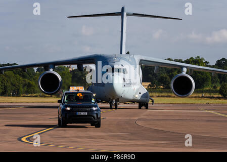 Japan Air Self Defense Force JASDF Japanese Air Force Kawasaki C2 piano di trasporto in arrivo per il Royal International Air Tattoo, RIAT 2018, RAF Fairford airshow di seguito un follow me escort Land Rover Auto Foto Stock