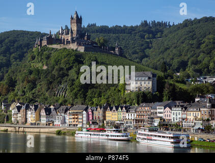 Il Castello di Reichsburg (), con la sua vigna, torreggia su colorato a struttura mista in legno e muratura edifici lungo la sponda del Fiume Mosella, a Cochem, Germania. Foto Stock