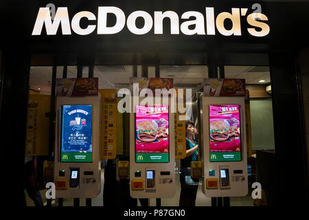 I clienti ordinano cibo in automated self-ordering kiosk presso un McDonald's ristorante fast food in Hong Kong. Foto Stock