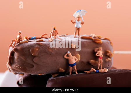 Primo piano della miniatura alcune persone che indossano il costume da bagno rilassante su alcuni di gelato al cioccolato bar Foto Stock