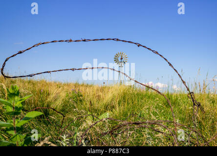 Un groviglio di rusty il filo spinato giace dimenticato nei pressi di un mulino a vento nel Nebraska Sandhills. La Sandhills sono una funzione ecologica unica per Nebraska. Foto Stock