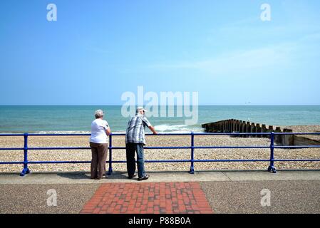 Coppia di anziani appoggiata sul lungomare di ringhiere che guarda al mare in una calda giornata estiva, Eastbourne East Sussex England Regno Unito Foto Stock