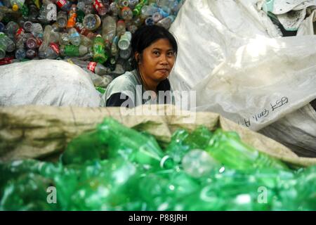 ANGONO, Rizal, Filippine - luglio 4 2018: i lavoratori di un recupero dei materiali facility pongono e sorriso per la fotocamera. Foto Stock