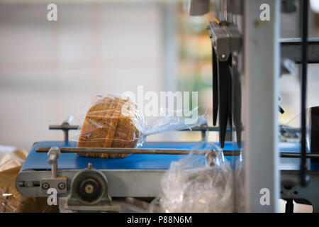 Linea industriale per il confezionamento di prodotti da forno. Confezionamento di pane in fabbrica.La macchina per il taglio e confezionamento in una fabbrica per la produzione Foto Stock