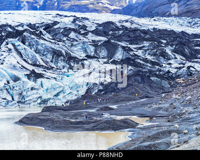 21 Aprile 2018: Sud Islanda - i turisti al ghiacciaio Solheimajokull linguetta e il lago glaciale. Foto Stock