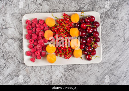 Mescolati molti diversi colorata frutta di stagione, lamponi, ciliegie, albicocche, sulla piastra, vista dall'alto, spazio di copia Foto Stock