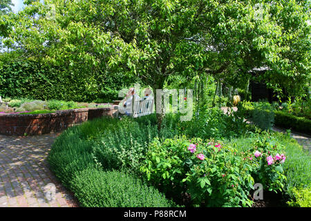 Coppia matura seduti in un tradizionale English country garden, RHS Rosemoor, Torrington, Devon, Regno Unito - Giovanni Gollop Foto Stock