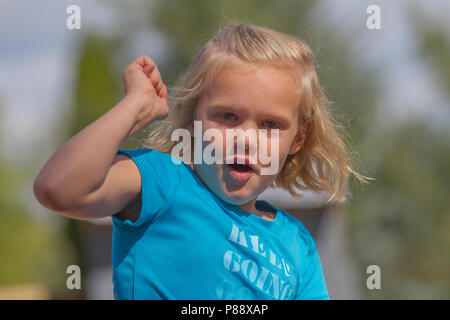 Giovane ragazza bionda, guarda direttamente nella fotocamera, sorridente, e rasiing braccio. Modello rilasciato #113 Foto Stock