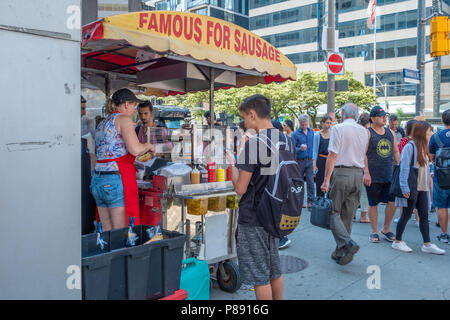 Distributore vende la sua salsicce provenienti da un carrello su una strada trafficata in Toronto Ontario Canada. Foto Stock