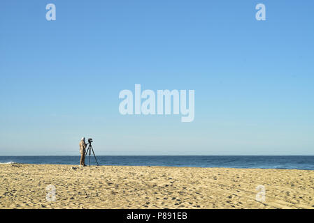 Cameraman con videocamera su Stativi treppiede tropicale sulla spiaggia di sabbia di Baja, Messico Foto Stock