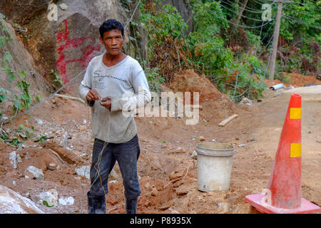 Lavoratori edili provenienti dal Myanmar sono la costruzione di nuove strade attraverso la giungla che copre le montagne dell'isola thailandese di Koh Phangan, Thailandia Foto Stock