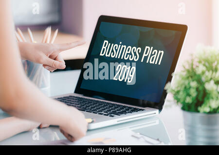 La gente di affari riuniti nella parte anteriore del computer portatile con schermo piano di Business 2019 parola sulla scrivania in ufficio,Digital concetto di marketing Foto Stock