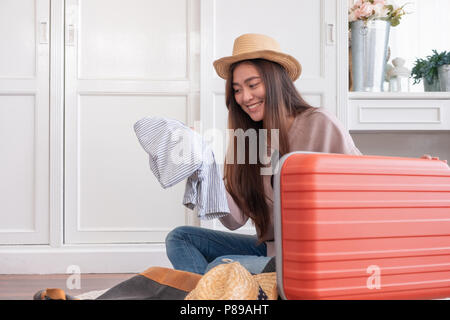 Giovane donna asiatica traveler preparare il panno a orange valigia per vacanze a casa.backpacker concetto di viaggio Foto Stock