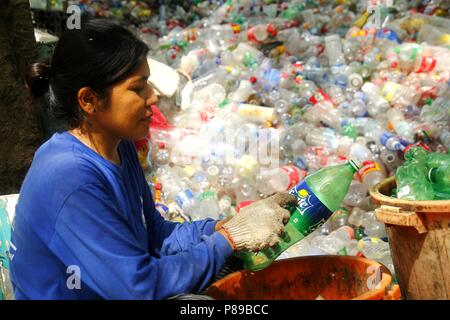 ANGONO, Rizal, Filippine - luglio 4 2018: i lavoratori di un recupero dei materiali facility preparare le bottiglie di plastica per il corretto riciclaggio. Foto Stock