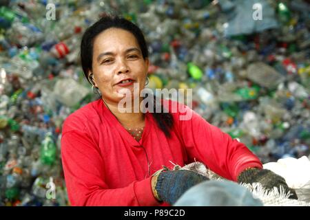 ANGONO, Rizal, Filippine - luglio 4 2018: i lavoratori di un recupero dei materiali facility pongono e sorriso per la fotocamera. Foto Stock