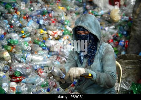 ANGONO, Rizal, Filippine - luglio 4 2018: i lavoratori di un recupero dei materiali facility preparare le bottiglie di plastica per il corretto riciclaggio. Foto Stock