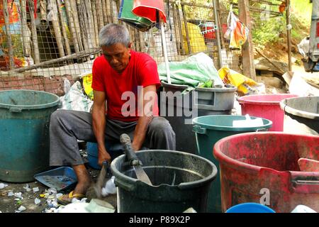 ANGONO, Rizal, Filippine - luglio 4 2018: i lavoratori di un recupero dei materiali facility preparare le bottiglie di plastica per il corretto riciclaggio. Foto Stock