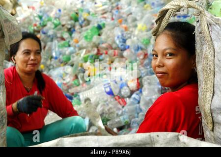 ANGONO, Rizal, Filippine - luglio 4 2018: i lavoratori di un recupero dei materiali facility pongono e sorriso per la fotocamera. Foto Stock