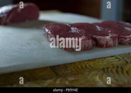 Carni disposto sul tagliere in macelleria Foto Stock