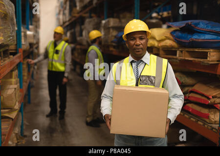 Personale maschile tenendo la scatola di cartone in magazzino Foto Stock