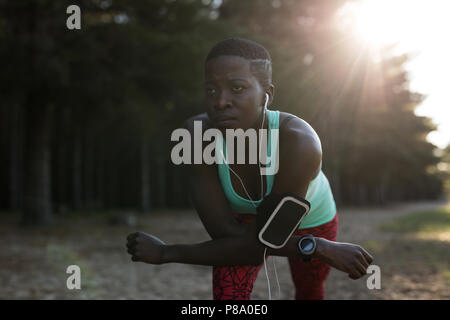 Atleta femminile ascoltare musica mentre si fa allenamento mattutino Foto Stock
