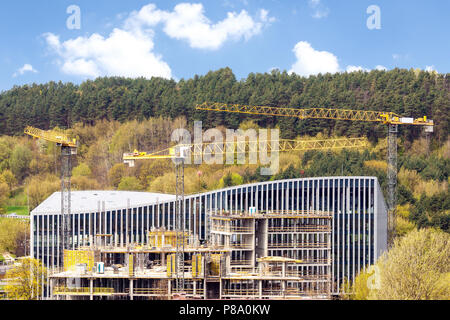 Vista panoramica di industriale sito in costruzione di gru sullo sfondo di verdi colline Foto Stock