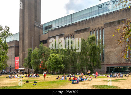 Gruppi di persone, soprattutto i bambini e gli adolescenti, rilassante e avente un pic-nic sul prato fuori la Tate Modern , Bankside, London, England, Regno Unito Foto Stock