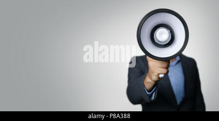 Annuncio - imprenditore con megafono di fronte faccia su sfondo grigio Foto Stock