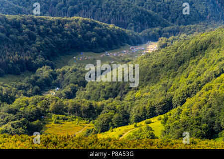 Un campo in tenda in agguato in mezzo al verde di boschi che cresce su pendii ripidi. Con accogliente prati e strade. . Per il vostro design Foto Stock