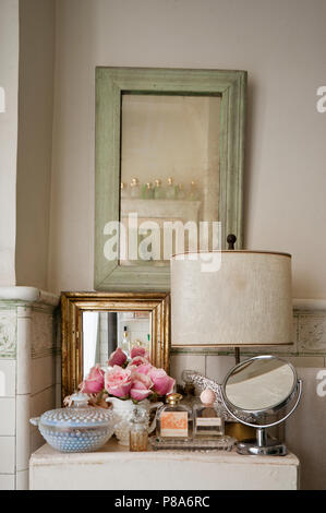 Una selezione di specchi e profumi sul cabinet in shabby chic bagno piastrellato Foto Stock